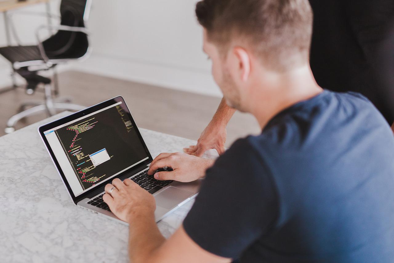 Two people at a laptop with HTML code